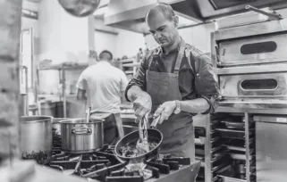 A man in a restaurant kitchen cooking over a stove