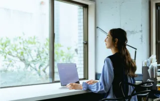 woman sitting on laptop looking out window