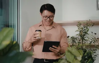 man holding coffee looking at tablet