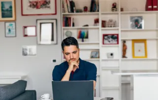 man sitting at computer at home looking at screen