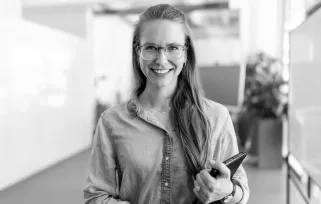 Woman with glasses carrying a clipboard in an office