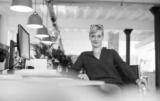 woman sitting side on at desk in office looking at camera