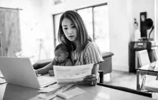 Frau sitzt mit Baby vor dem PC.