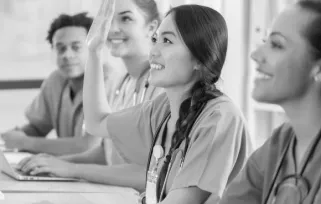 4 nurses sitting at a table smiling at someone out of frame