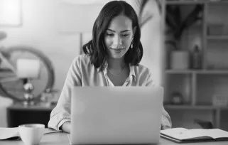 woman sitting at desk writing on laptop