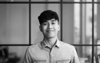 Young man standing in office smiling at camera