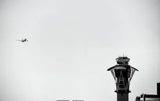 air traffic control tower with plane flying overhead