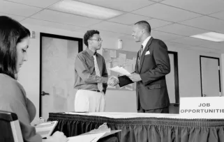 two men shaking hands next to career fair table