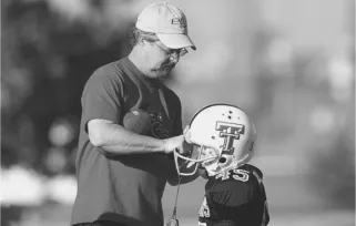 football coach putting a football helmet on a child