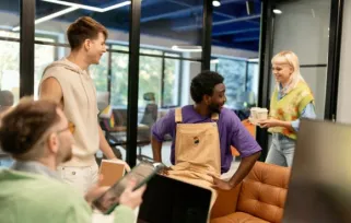 Smiling woman giving coffee to her colleagues in the modern IT company