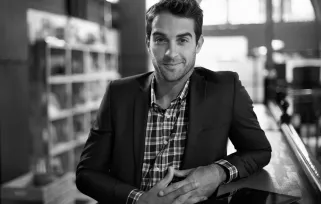 man leaning on reception desk smiling at camera