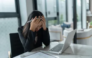 women appears stressed in front of laptop at desk at work