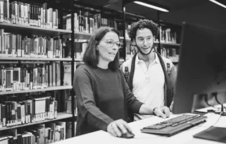 librarian helping customer look up a book on a computer