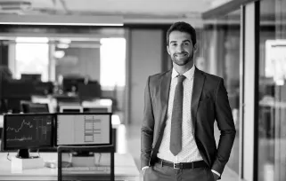 man in a suit standing in an office smiling at camera