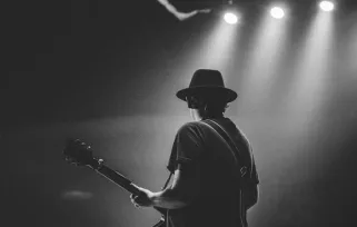 musician playing guitar under stage lights