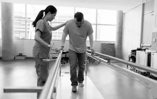 occupational therapist helping patient to walk