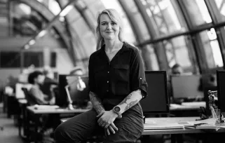 woman sitting on the edge of a desk smiling at the camera