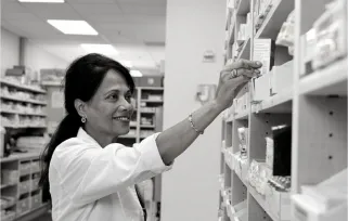 pharmacist taking medicine off pharmacy shelf