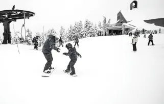 ski instructor teaching kid to snowboard