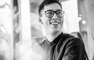 Man wearing glasses smiling at someone to his left