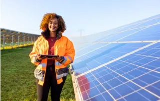 woman in high vis jacket standing outdoors next to solar panels