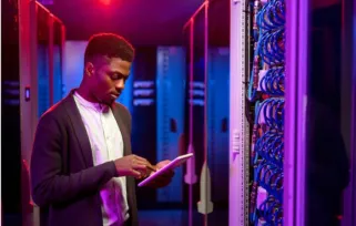 Young man in server room using tablet