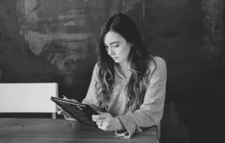 woman sitting at table reading from a tablet