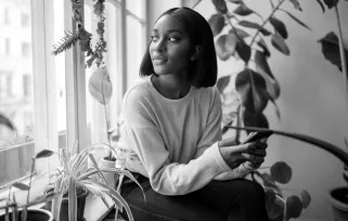 woman at home on phone looking out window