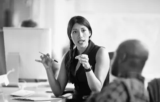 A woman sitting at her desk is having a conversation with a difficult coworker.