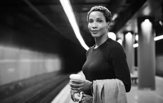 Frau wartet mit Kaffee auf die Bahn.