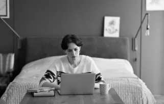 woman sitting at laptop in bedroom