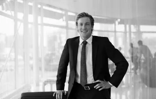 man in suit standing with hand on hip smiling at camera