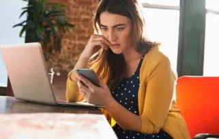 young woman looking at phone appearing stressed