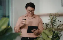 man holding coffee looking at tablet