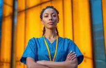 woman in scrubs with arms crossed looking at the camera