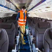 Man cleaner working in airplane salon cleaning airplane after customer offboard