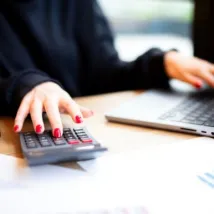 Businesswoman working in office using calculator with laptop open