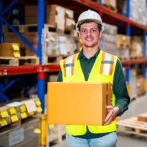male worker standing in a large warehouse full of boxes ready to distribute the package accordingly