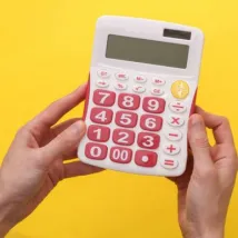hand model holding calculator with yellow background