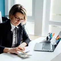 businesswoman or accountant using a calculator, graphs, and charts to analyze market data