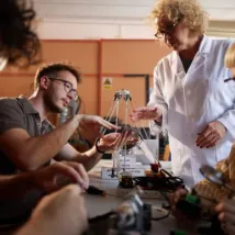 Mature professor supervising her high school students who are working on a science project in laboratory