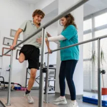 Young man uses parallel bars in a rehab center