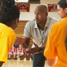 Coach talking to basketball team during game in gym