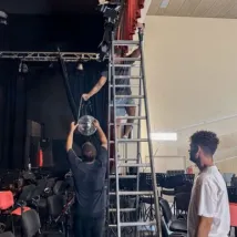 Technician on top of a ladder preparing the theatrical stage for a concert